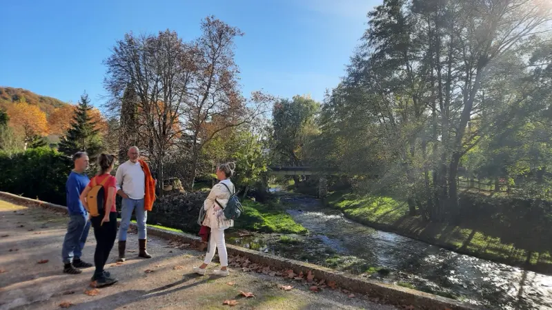 Wandelaars langs een beek in de herfstzon